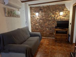 un soggiorno con divano e parete in pietra di LA COVETA RURaL a Vilafamés