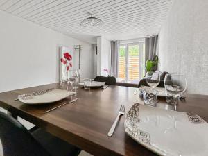 Un comedor con una mesa de madera con copas de vino. en Parking privé & terrasse ensoleillée, en Illzach 13 fotos más
