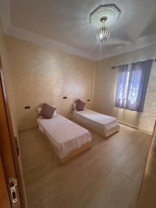 una habitación con dos camas y una ventana en Sinbad Hostel, en Merzouga