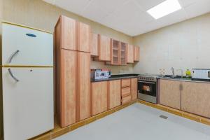 a kitchen with wooden cabinets and a refrigerator at The Sunshine Farm by Al Dana Paradise Luxury 6BR Secluded Nature Mountains in Khor Fakkan