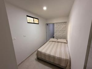a small bed in a white room with a window at Apartamento Montecristo in Barranquilla
