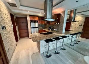 a kitchen with a island with bar stools at Muy centrico, acogedor y como apartamento en La Viña a solo pasos de la AV BOLIVAR NORTE in Valencia