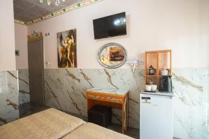 a room with a bed and a desk and a tv on the wall at Studios Nopi-Zoi in Skiathos