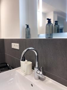 a bathroom sink with a faucet and two bottles on a shelf at Stilvolle helle Wohnung im Zentrum in Osnabrück
