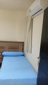 a bedroom with a bed with blue sheets and a window at شالية لاسرينا ميني ايجيبت ـ العين السخنة in Ain Sokhna