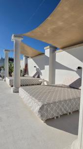 a row of beds sitting under a pavilion at Oasi Cleopatra Luxury Suite B&B Puglia Salento in San Pietro in Bevagna