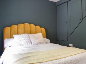 ein Schlafzimmer mit einem großen Bett mit einem gelben Kopfteil in der Unterkunft Hillside Cottage in Glossop + 4 Fotos