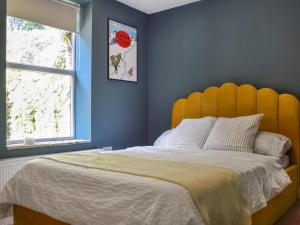 ein Schlafzimmer mit einem großen Bett mit einem gelben Kopfteil in der Unterkunft Hillside Cottage in Glossop