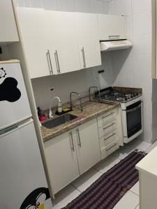 a kitchen with white cabinets and a sink and a refrigerator at Enseada apartment accommodates up to 8 people in Guarujá +8 photos
