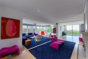 a living room with pink chairs and a blue rug at Vine Cottage in Blakeney