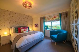 a bedroom with a bed and a blue chair at Vine Cottage in Blakeney