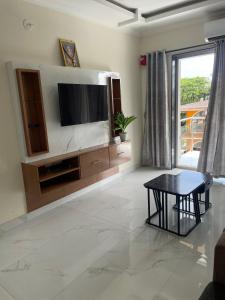 アーポラにあるRosebank service Apartmentのテレビとテーブルのあるリビングルーム