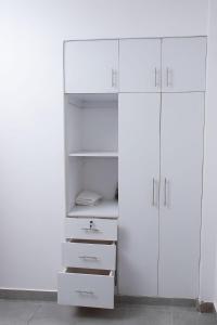 BusiaにあるKayla Suitesの白いクローゼット(白いキャビネットと引き出し付)