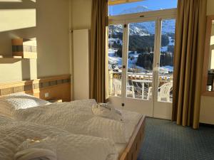 a hotel room with two beds and a large window at Hotel Victoria Lauberhorn Wengen, a Faern Collection Hotel in Wengen