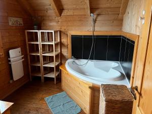a bathroom with a tub in a wooden cabin at Chalet de Lucie et Lison in Erckartswiller