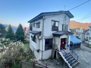 a white house with a staircase in front of it at E KI house ski school in Yuzawa