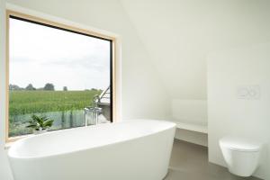 a white bathroom with a large window and a tub at Haus am See in Gosdorf