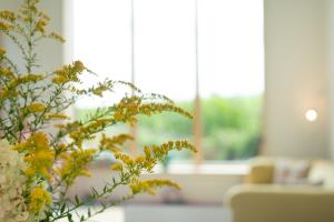 a vase filled with yellow flowers next to a couch at Haus am See in Gosdorf