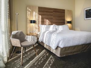une chambre d'hôtel avec un lit et une chaise dans l'établissement Mercure Concepcion, à Concepción