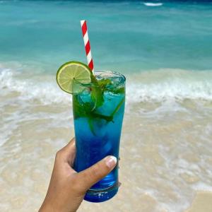 a hand holding a blue drink with a lime on the beach at Portia beach grand 2 in Male City