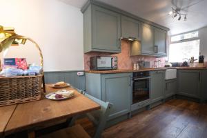eine Küche mit grünen Schränken und einem Holztisch in der Unterkunft Cosy Cottage in Youlgreave