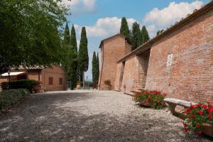 a courtyard of a brick building with trees and flowers at Castello di Leonina Relais - Adults Only in Siena +43 photos