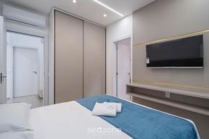 Un dormitorio con una cama y un televisor de pantalla plana. en Apto 2Hab c/ balcón, próx. playa Itapema RGO702, en Meia Praia