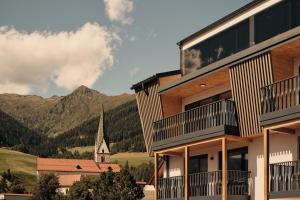 een gebouw met uitzicht op een kerk en bergen bij MONTARA living mountain air in Terento
