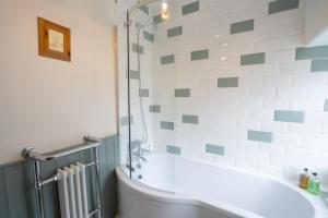 eine Badewanne im Bad mit grünen und weißen Fliesen in der Unterkunft Cosy Cottage in Youlgreave + 29 Fotos