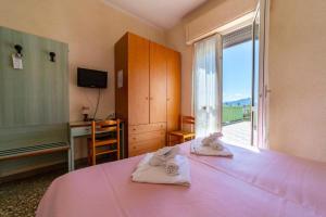 a bedroom with a pink bed with towels on it at Albergo Regina Mundi in Pietra Ligure
