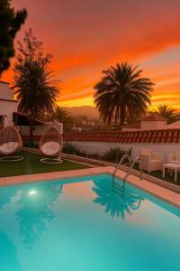 a swimming pool with a sunset in the background at Hotel Rural Villa del Monte in Santa Brígida