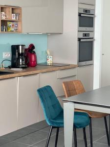 a kitchen with white cabinets and a table and chairs at Villa Marie 2 Appartement tout confort climatisé 1 chambre proche plage in Le Grau-du-Roi
