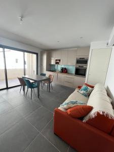 a living room with a red couch and a table at Villa Marie 2 Appartement tout confort climatisé 1 chambre proche plage in Le Grau-du-Roi +51 photos