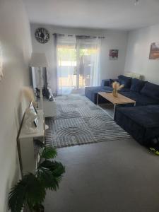 ein Wohnzimmer mit einem blauen Sofa und einem Tisch in der Unterkunft Appartement partagé in Méry-sur-Oise