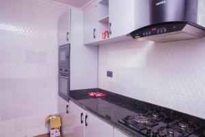 a kitchen with white walls and a stove top oven at Boss Apartment in Ikeja