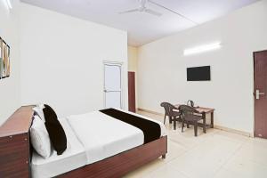 Un dormitorio con una cama y una mesa con sillas. en Hotel O Golden Sky, en Noida