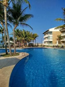 a large swimming pool with palm trees and a building at Apartamento boa vida in Aquiraz