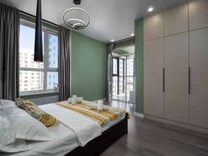 a bedroom with a large bed and large windows at Кристалл 5-12 in Almaty