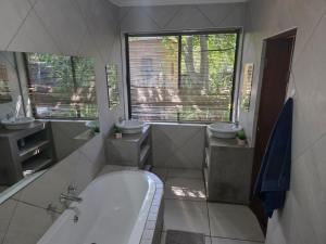 een badkamer met 2 wastafels, een bad en 2 spiegels bij The Pot in Pretoria +39 foto's