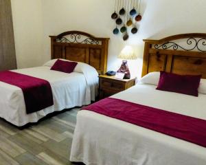 ein Hotelzimmer mit 2 Betten mit roter und weißer Bettwäsche in der Unterkunft Hotel Hacienda Bugambilias La Paz in La Paz