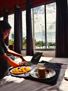 una mujer sentada en una cama con un plato de comida en Louis Backpackers Hostel, en Kochi