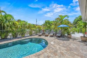 a swimming pool with chairs and an umbrella at The Solaster in Siesta Key