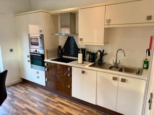 a kitchen with white cabinets and a sink at Bloom Apartments - City Centre - Gated Parking in Manchester +53 photos