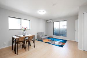a white living room with a table and chairs and a couch at 青嵐居 天王寺難波近く 無料駐車2台OK 一戸建て4LDK貸切最大15名ok 家族旅行最適 in Osaka