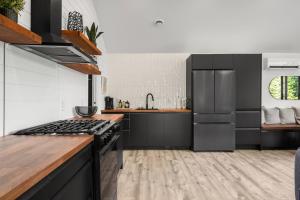 a kitchen with black and white appliances and wooden floors at Nalu Retreat Lakeside Villa in Porters Lake +3 photos