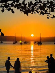 a group of people standing on the beach watching the sunset at House in Santo Antônio in Florianópolis