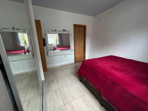 a bedroom with a red bed and two windows at House in Santo Antônio in Florianópolis