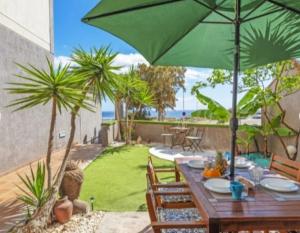 a wooden table with a green umbrella on a patio at Chalet en la Playa in El Médano