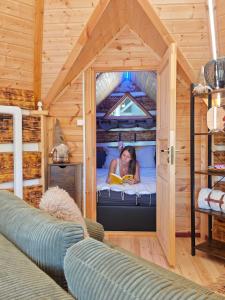 Una mujer acostada en la cama en una casa en el árbol en Le Féérik, en Foncine-le-Haut