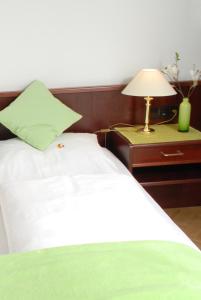 a bed with a green pillow and a lamp on a table at Altstadt Hotel Meppen in Meppen